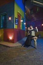 Hispanic couple performing tango on city street