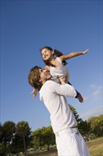 Hispanic father lifting daughter into the air
