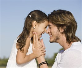Hispanic father and daughter smiling at one another