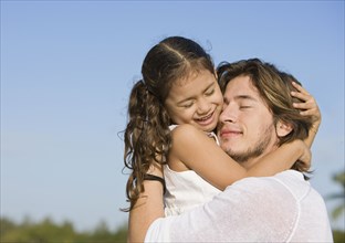 Hispanic father hugging daughter