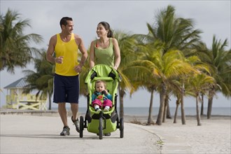 Hispanic couple pushing baby in jogging stroller