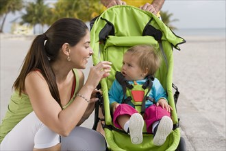 Hispanic woman checking on baby in jogging stroller