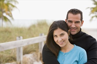 Hispanic couple hugging near ocean