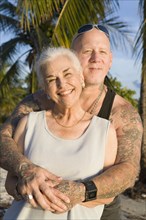 Mother and tattooed son hugging at the beach