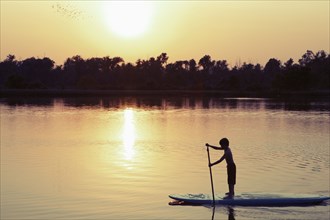 Caucasian boy on paddleboard on lake