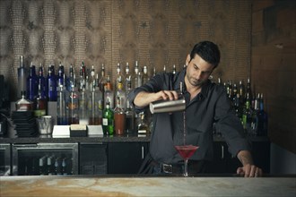 Caucasian bartender pouring drinks at bar