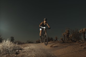 Woman riding mountain bike in desert