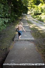 Caucasian boy climbing stairs near rural path