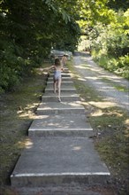 Caucasian children climbing stairs near rural path