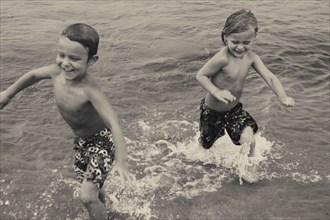 Caucasian boys playing in lake