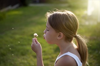 Caucasian girl blowing seeds off dandelion