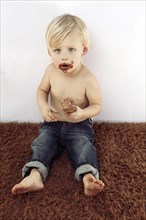 Messy Caucasian boy eating chocolate ice cream cone