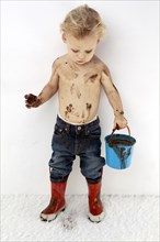 Messy Caucasian boy playing with mud on white carpet
