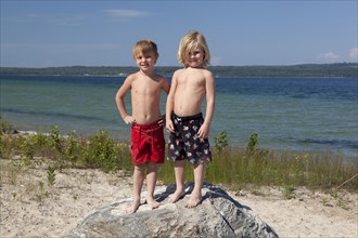 Caucasian boys standing on rock on beach