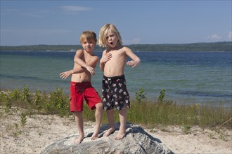 Caucasian boys standing on rock at beach