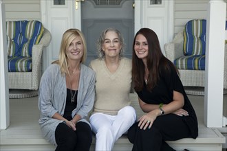 Caucasian mother and daughters smiling on front porch