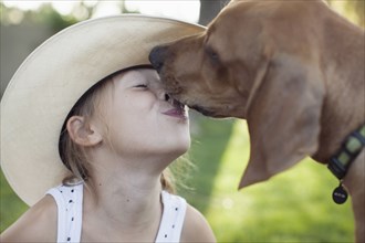 Caucasian girl kissing dog outdoors