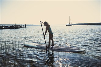 Caucasian girl standing on paddleboard in lake