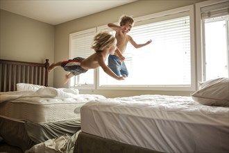 Caucasian boys jumping on beds