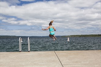 Caucasian girl jumping into lake