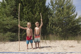 Caucasian boys holding sticks on beach