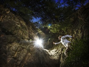 Caucasian man reaching for light in forest