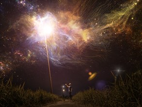 Caucasian man reaching towards light in starry night sky