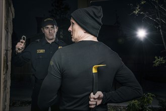 Caucasian burglar hiding crowbar from police office holding handcuffs