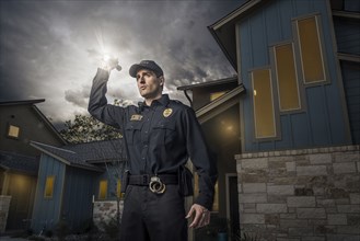 Caucasian police officer shining flashlight near house