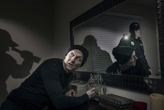 Caucasian police officer shining flashlight on house burglar