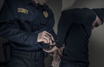 Caucasian police officer handcuffing burglar