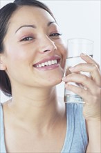 Young woman holding glass of water against face