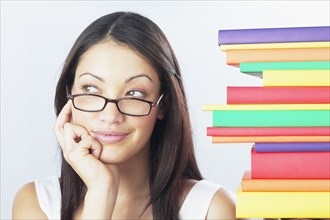 Woman wearing eyeglasses next to stack of books