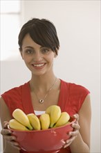 Young woman holding bowl of bananas