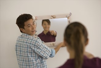 Asian couple hanging mirror