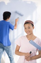 Asian couple painting interior of house