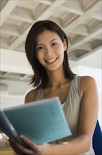 Asian woman holding open notebook