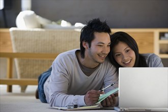 Asian couple looking at laptop