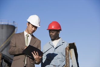 Multi-ethnic businessman and construction worker looking at paperwork