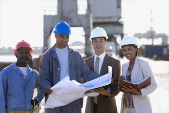 Multi-ethnic businesspeople and construction workers with blueprints