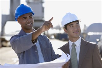 Multi-ethnic businessman and construction worker pointing