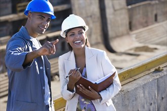 African American businesswoman and construction worker pointing