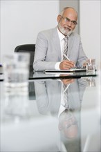 Senior African businessman writing at table