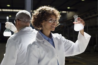 African scientists examining beakers of liquid in factory