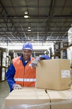 African worker leaning on boxes in warehouse