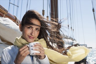 Caucasian woman drinking coffee on sailboat