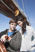 Caucasian couple steering sailboat