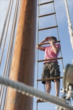 Caucasian man looking at view from ladder on sailboat
