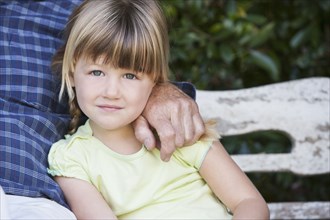 Caucasian girl sitting with grandfather on bench