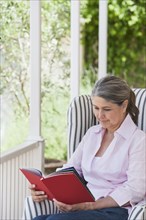 Senior Caucasian woman reading on porch